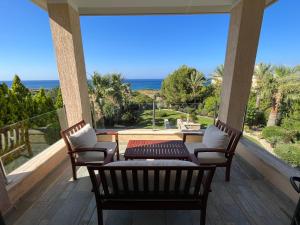 porche con sillas y mesa y vistas al océano en Amorosa Beach Villa 14, en Neo Chorio