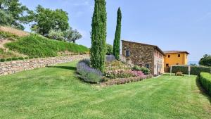 einen Garten mit zwei Bäumen und einer Steinmauer in der Unterkunft Il Solatio in Cavriglia