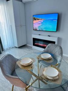 sala de estar con mesa, sillas y TV en Premium Aparthotel La Mirada, en Mamaia Nord – Năvodari