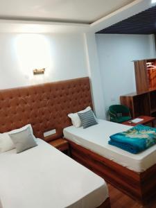a hotel room with two beds and a chair at Hotel Florence in Siliguri