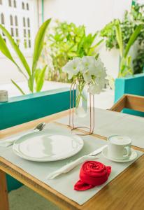 a table with a white plate and a vase with flowers at Palm Rest Maldives in Magoodhoo