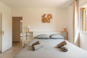 a white bedroom with a large bed with two pillows at Villa vue mer presqu'ile de giens avec piscine in Hyères