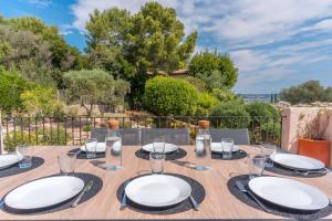 une table en bois avec des assiettes et des verres dans l'établissement Villa vue mer presqu'ile de giens avec piscine, à Hyères