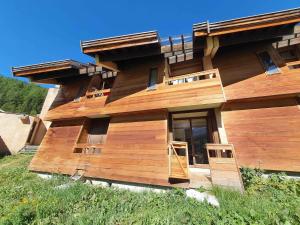 a wooden house with a deck on a hill at Duplex 6 personnes, VARS LES CLAUX, Skis aux pieds in Vars