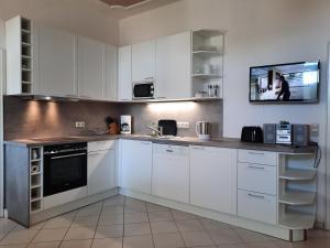 eine Küche mit weißen Schränken und einem TV an der Wand in der Unterkunft Villa Schering App. EG links in Heringsdorf + 25 Fotos