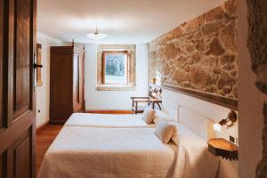 a bedroom with two beds and a stone wall at Casa Do Romualdo in Vilela