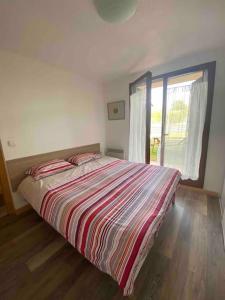een slaapkamer met een bed met een gestreept dekbed en een raam bij Location appartement in Sainte-Léocadie