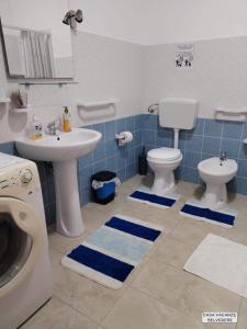 bagno con lavandino, servizi igienici e piastrelle blu di Casa Belvedere a Portopalo