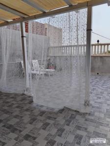 a covered patio with white curtains and a chair at Casa Belvedere in Portopalo