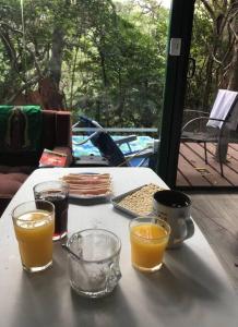 una mesa con dos vasos de jugo de naranja. en Cabaña de montaña espectacular, en Liberia