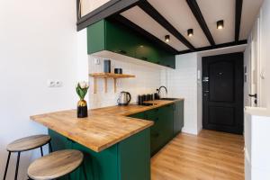 a kitchen with green cabinets and wooden floors at Golden Apartments Warsaw - Stylish Luxury, Złota Street in Warsaw +4 photos