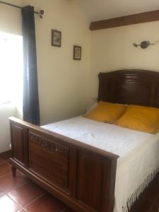 una camera da letto con un grande letto in legno con lenzuola bianche di Maison de village dans joli hameau médiéval a La Tour-sur-Orb