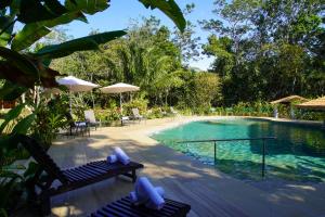 a pool with chairs and umbrellas next to a resort at Natural Lodge Caño Negro in Caño Negro