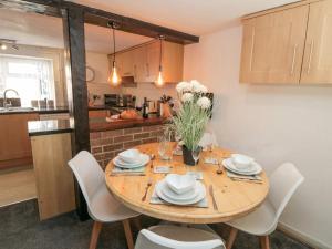 cocina con mesa de madera y sillas blancas en The Hideaway, en Scarborough