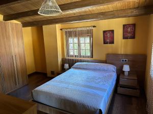 1 dormitorio con 1 cama con edredón azul y ventana en Casa Miravalles Fornela, 