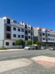 a large white building with cars parked in front of it at Mar de Covelo in Pontevedra