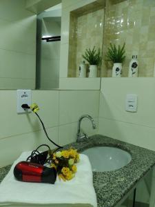 Un mostrador de baño con lavabo y una botella roja. en A 5 km do aeroporto no centro do Nucleo Bandeirante, en Brasilia
