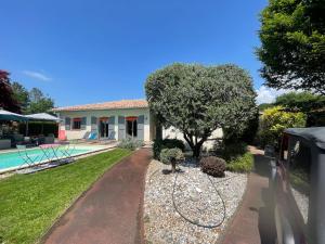 une maison avec un arbre et une piscine dans l'établissement Villa avec piscine Andernos les Bains, à Andernos-les-Bains