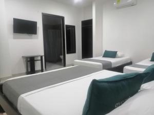 a room with three beds and a flat screen tv at Aveiro Hotel in Cúcuta