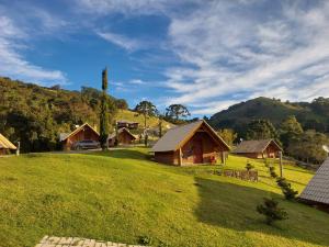 uma casa num campo verde com montanhas ao fundo em Pousada Vista do Paraíso em Monte Verde