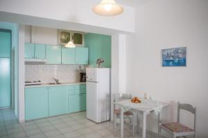 a kitchen with blue cabinets and a table and a refrigerator at Mary's Studios in Agia Pelagia