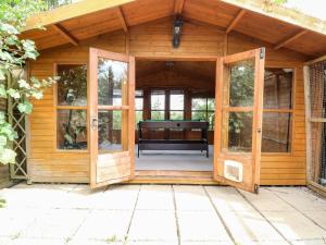 une porte ouverte d'un hangar en bois avec un banc à l'intérieur dans l'établissement Vintner's Cottage, à Norwich