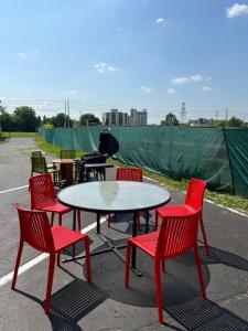 einen Tisch und vier rote Stühle sowie einen weißen Tisch und Stühle in der Unterkunft Diplomat Inn in Niagara Falls