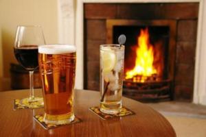 two glasses of beer on a table with a fireplace at Beansheaf Hotel in Pickering