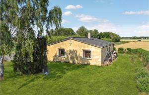 una pequeña casa en un campo de hierba con un árbol en Awesome Home In Bandholm With 3 Bedrooms And Wifi, en Bandholm