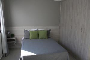 um pequeno quarto com uma cama com almofadas verdes em Flat Noroeste Square by CentoEdez em Brasília