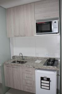 a kitchen with a sink and a microwave at Flat Noroeste Square by CentoEdez in Brasilia