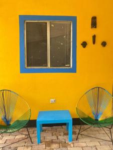 dos sillas y una mesa azul frente a una pared amarilla en Colors House, en Fusagasuga