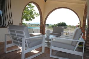 eine Terrasse mit zwei weißen Stühlen, einem Tisch und zwei Fenstern in der Unterkunft Alleinstehende Villa mit Pool-Finca Gabriela in Oliva