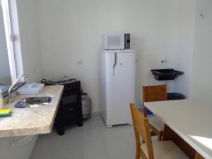 a kitchen with a refrigerator and a table and chairs at Sol Apartamento 4 - Quarto e sala com varanda e cozinha americana na praia do prea-CE in Prea