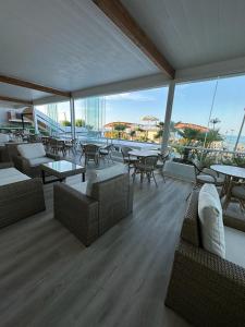Habitación grande con mesas, sofás, mesas y ventanas. en Hotel Costa Verde en Pineto