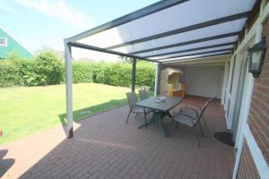a patio with a table and chairs on it at FH Norderpiep 22 Sauna u Kamin in Friedrichskoog-Spitze