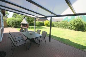 a patio with a table and chairs and a grill at FH Norderpiep 22 Sauna u Kamin in Friedrichskoog-Spitze