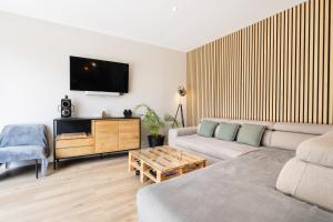 een woonkamer met een bank en een tv aan de muur bij * * La maison du bonheur * * Piscine chauffée in Fargues-Saint-Hilaire