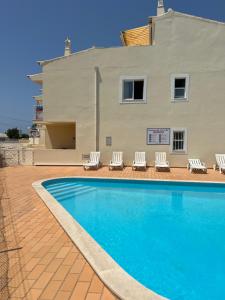 a swimming pool with lounge chairs and a building at Vilas do Mar - Studio in Carvoeiro