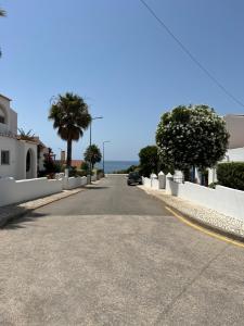 an empty street with palm trees and a car on the road at Vilas do Mar - Studio in Carvoeiro