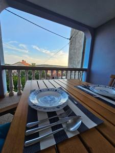 a table with a plate and silverware on a balcony at Apartman Lila in Čunski