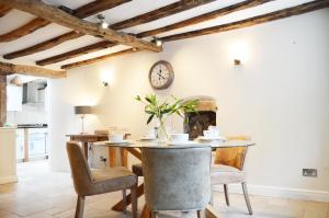 a dining room with a table and chairs and a clock on the wall at Goyt Cottage in Stockport