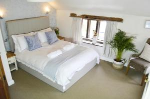 a bedroom with a large white bed and a chair at Goyt Cottage in Stockport