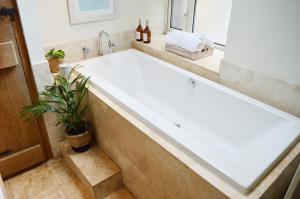 een groot bad in een badkamer met een plant bij Goyt Cottage in Stockport