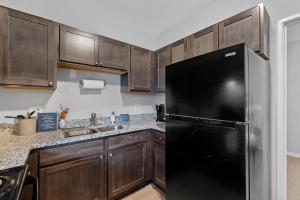 a black refrigerator in a kitchen with wooden cabinets at Flexhome Economy 1BR Apt MP10 - READ INFO in Milwaukee