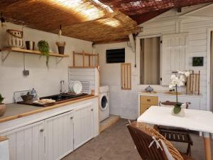 a kitchen with white cabinets and a table and a sink at LES BADAMIERS in Saint-Pierre
