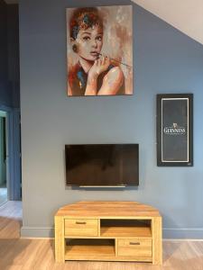 een woonkamer met een tv en een schilderij aan de muur bij The Angel Inn in Troed-y-rhiw