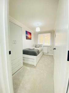 a white bedroom with a bed and a window at Vileto apartment in central Bournemouth in Bournemouth