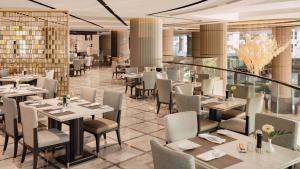 a restaurant with white tables and chairs and windows at InterContinental Bangkok by IHG in Bangkok
