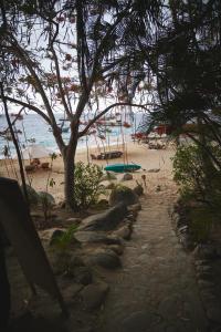 a beach with a tree and a surfboard on the beach at Casitas Maraika in Puerto Vallarta